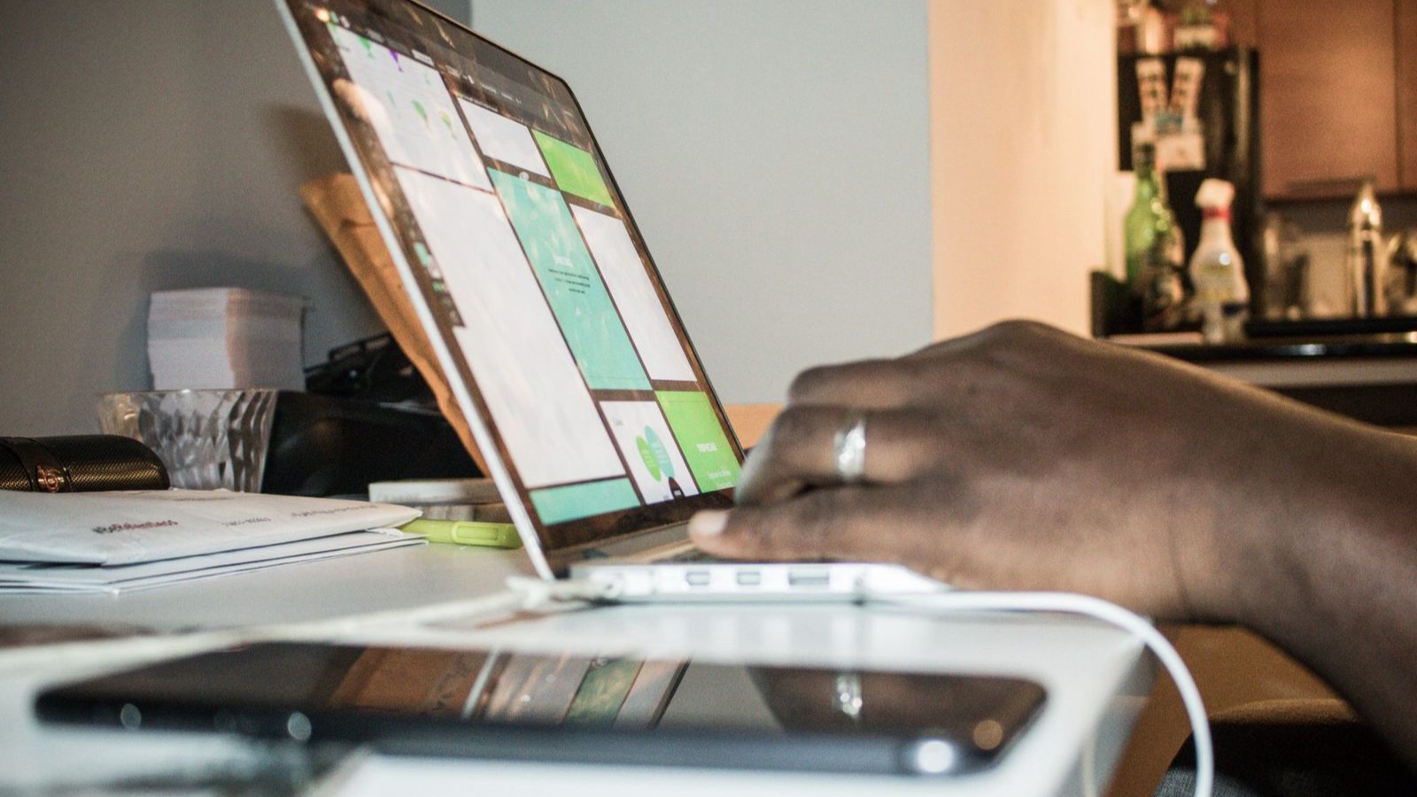 Focused setup of person working on a laptop in a home office environment with technology and documents.