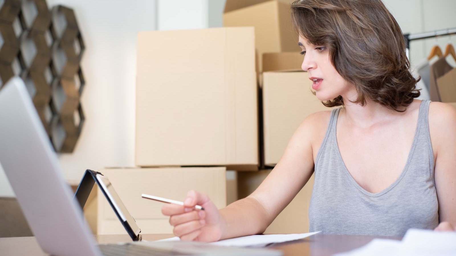 Choosing Ecommerce Software: Define Operations Before the Storefront Person preparing order notes beside a laptop and product packages