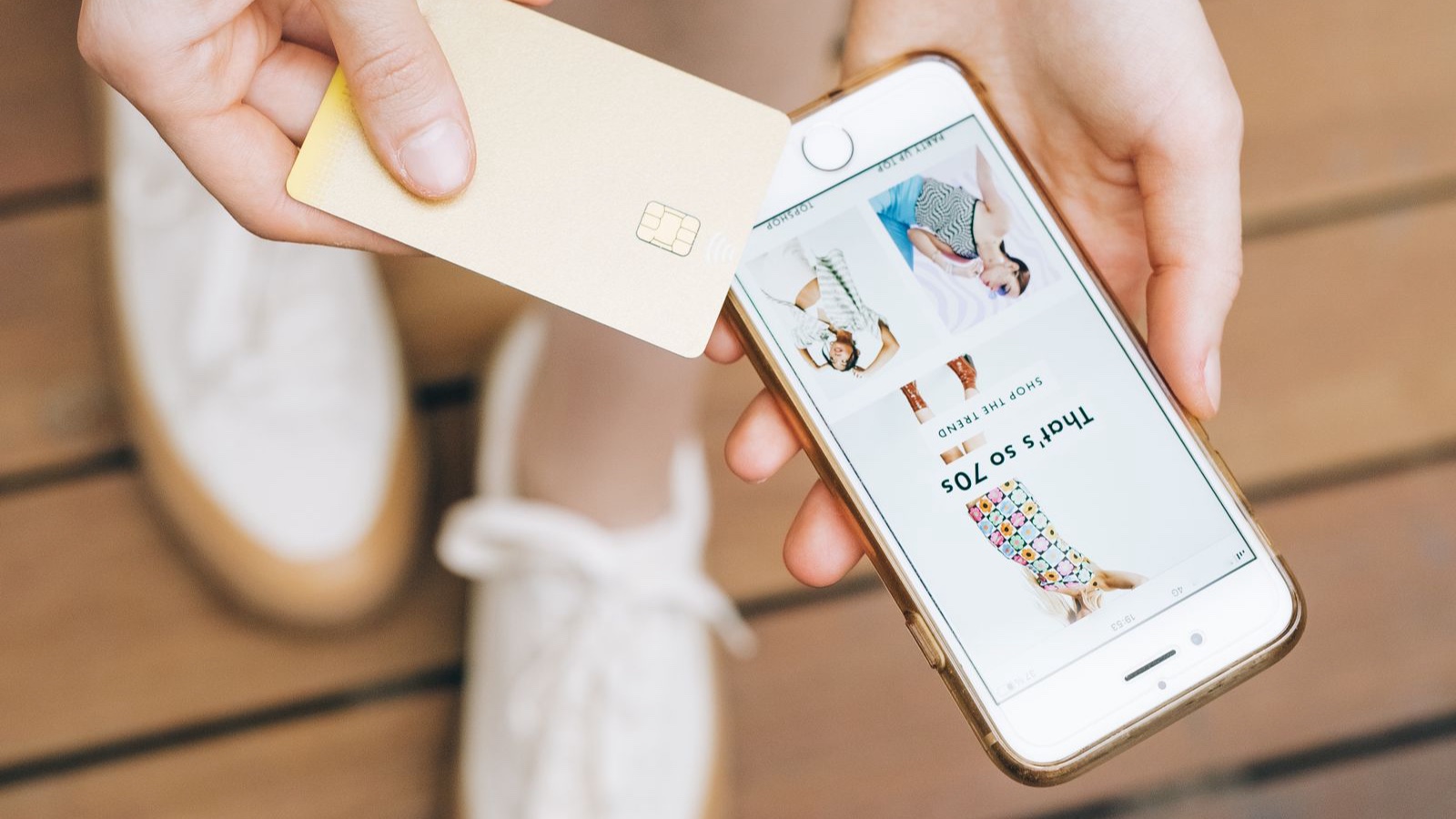 Person holding a payment card while browsing products on a phone