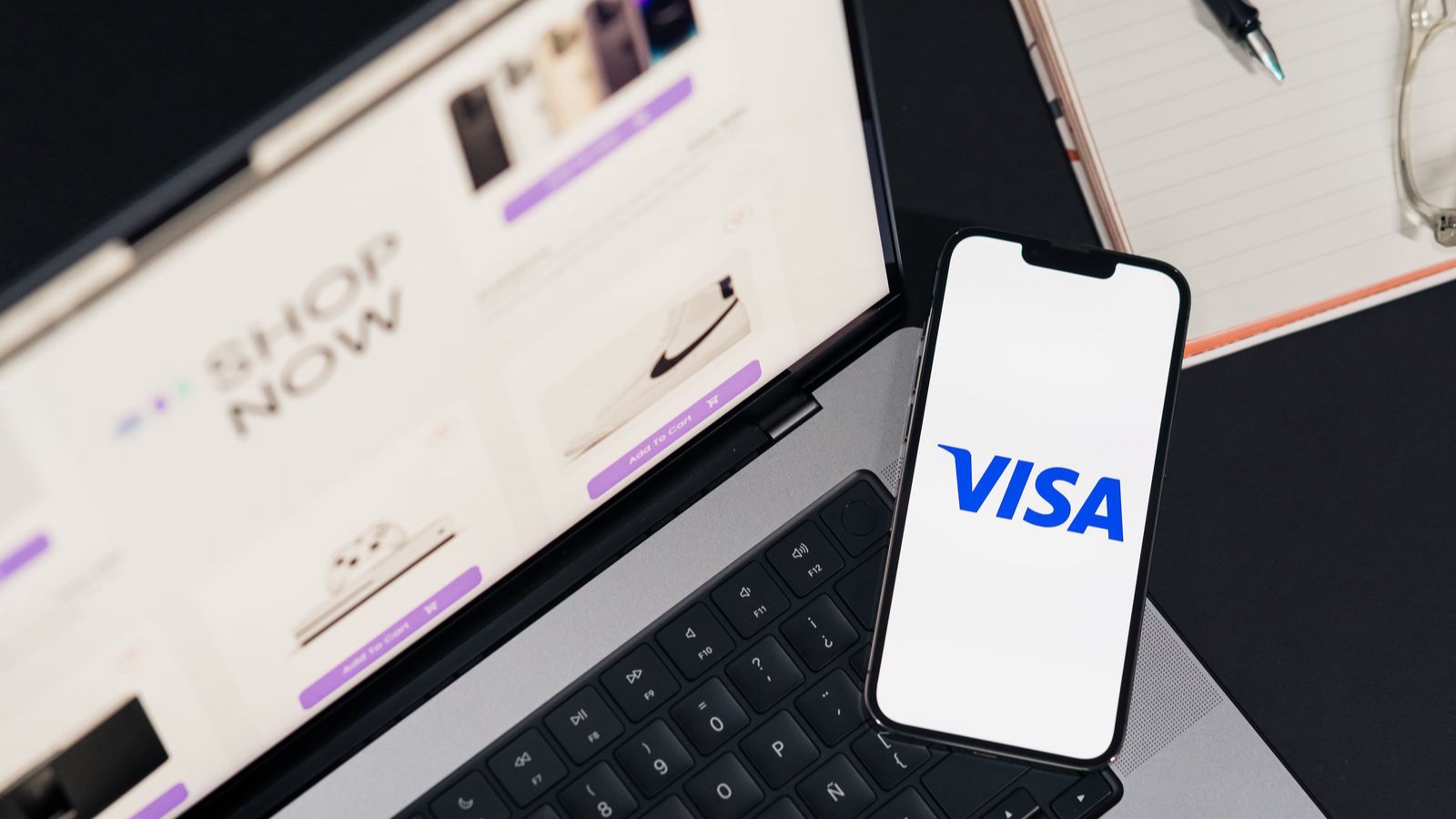 Phone showing a Visa payment screen beside a laptop storefront