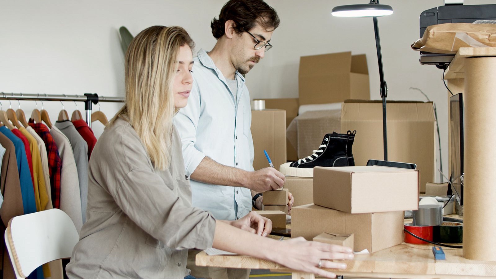 Two sellers preparing orders beside products and a computer