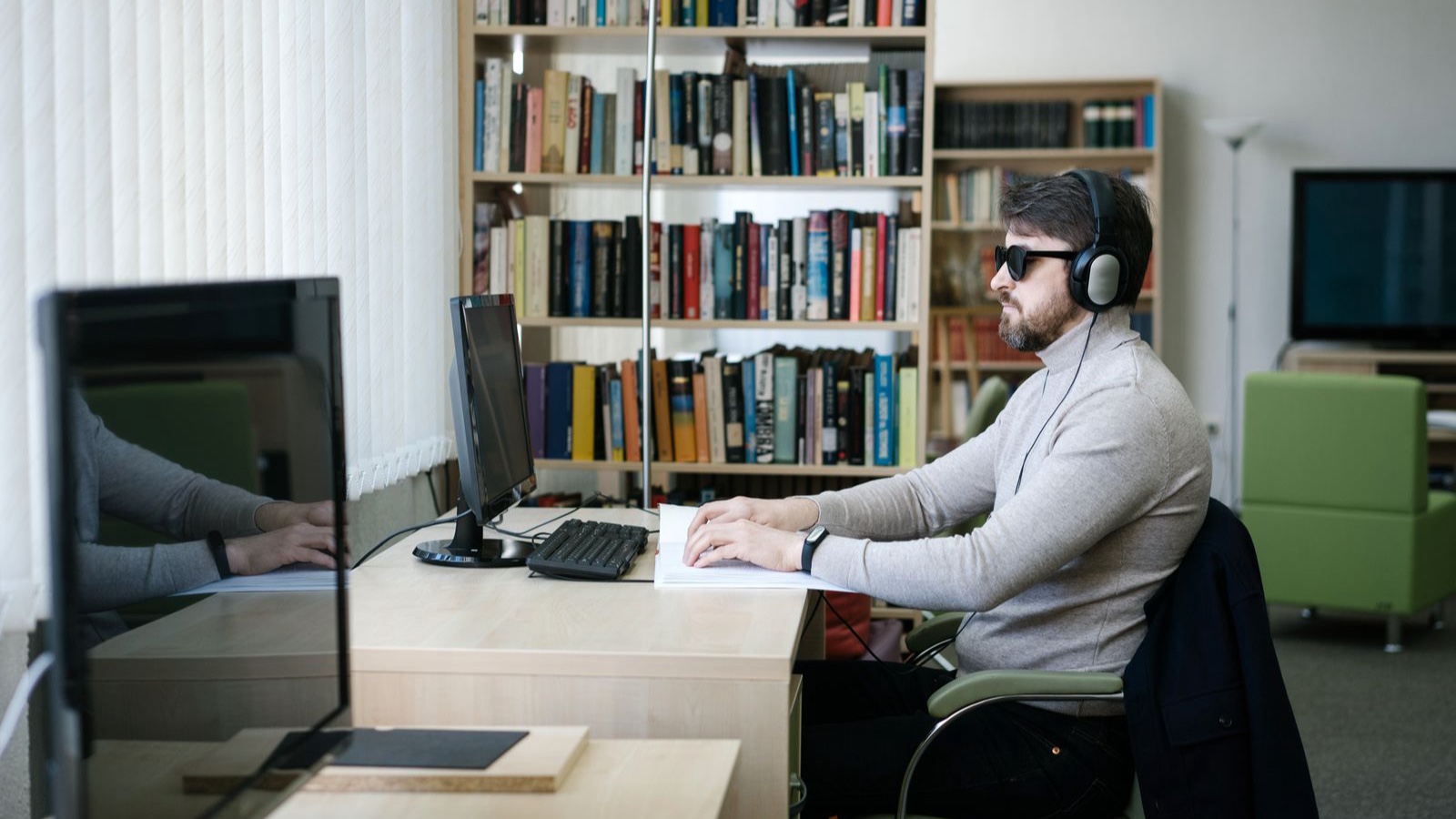 Web Accessibility: Practical Checks for Website Design Man using Braille book with headphones in modern library setting.