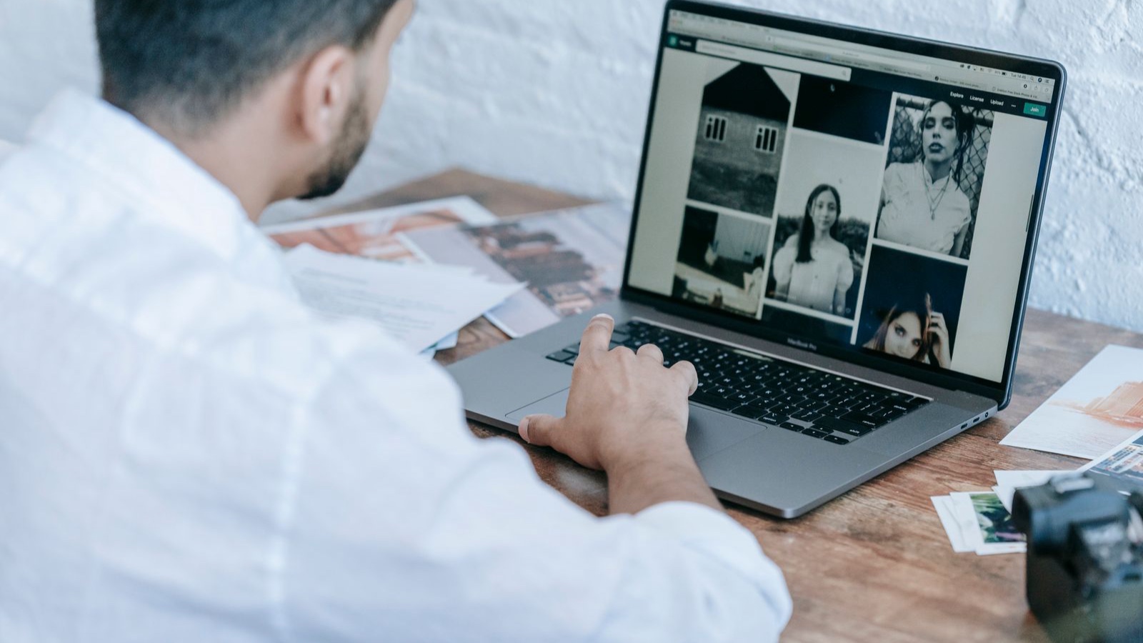 Side view of crop bearded male photographer using laptop while preparing pictures for publishing in modern workplace