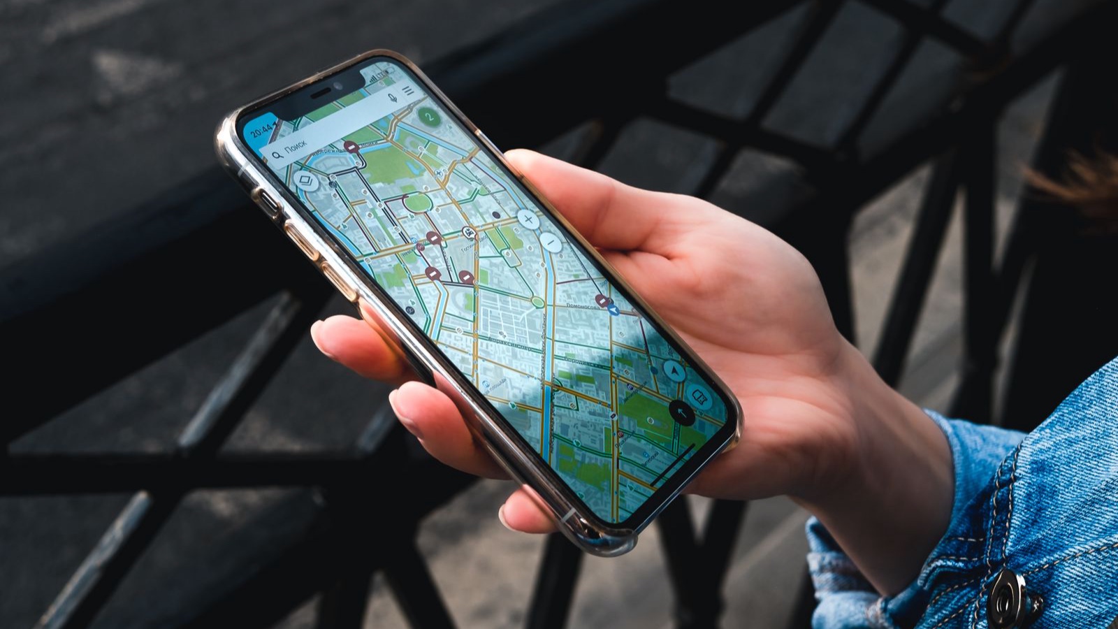 An outdoor close-up of a hand holding a smartphone displaying a map application.